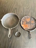 Three cast iron skillets of different sizes on dark surface
