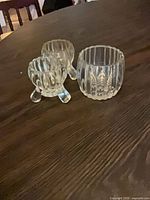 Two footed ribbed glass votive holders and one larger ribbed glass votive holder on table
