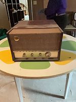 Front view of cabinet showing speaker grille, tuning dial and knobs