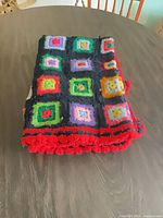 Afghan folded showing multicolor squares and red edge