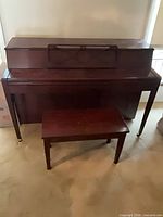 Front view of closed Kohler & Campbell upright piano with bench