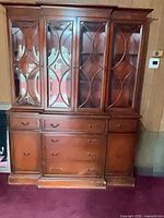 Front view of cherry wood china cabinet with glass doors and drawers closed