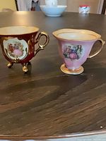 Front view of both miniature teacups showing color, shape and scenes