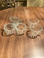 Five clear fluted glass pieces arranged together on table