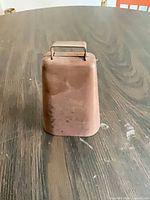 Front view of copper cow bell showing handle and patina