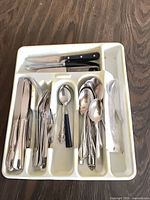 White plastic tray containing assorted knives, forks, spoons