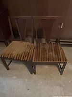 Front view of both chairs showing wooden frames and striped cushions