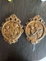 Both matching painted Rococo Revival plaques side-by-side showing size and ornate borders