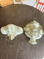 Pair of ornate plaster wall plaques on dark table