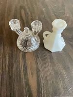 Clear pressed glass double-arm candle holder and white milk glass candle holder side by side