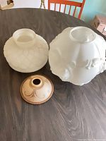 Two large white opalescent milk glass shades and one small cream-amber shade on table