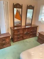 Full view of dresser flanked by nightstands and topped with mirrors