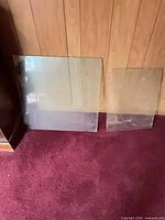 Both glass panels leaning against paneled wall on carpet