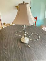 Full view of lamp on table showing base, stem, shade, cord