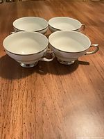 Four white Wallace Elegance teacups on tabletop, showing rim and foot trim