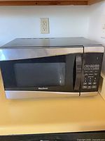 Front view of West Bend countertop microwave showing stainless and black exterior and control panel