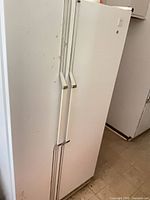 Full exterior view of white Whirlpool side-by-side refrigerator/freezer showing handles and overall condition