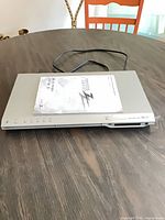 Zenith DVB412 DVD player with manual resting on top, power cord visible