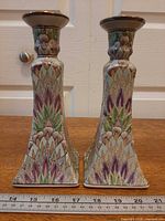 Front view of both porcelain candlestick holders showing square bases and floral pattern