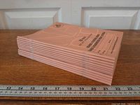 Side view of stacked pink exercise books showing quantity and thickness