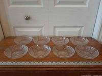 Eight clear glass bowls arranged in two rows with ruler for scale