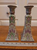 Front view of both candlestick holders showing floral design and height reference