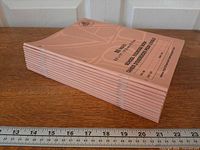 Stack of twelve pink North American Paper exercise books side view with ruler for scale