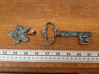 Key corkscrew and leaf hook next to ruler