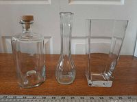 Front view of decanter, bud vase and rectangular vase side by side on table