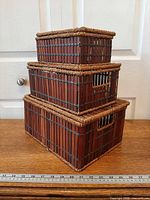 Three bamboo boxes stacked showing rope trim and side handle openings