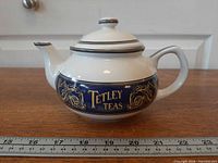 Left side profile of Tetley Teas teapot showing cobalt band and gold decoration with ruler for scale