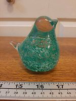 Front view of blown glass bird with ruler indicating height