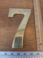 Front view of brass number 7 with rulers showing size