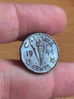 Reverse of 1944 Canada 5-cent coin displaying torch, maple leaves and date