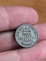 Reverse side of 1947 British sixpence coin showing crowned monogram, date and denomination