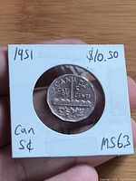 Reverse of 1951 Canadian 5-cent Sudbury Mine coin in holder, date and denomination visible