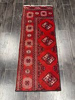 Full view of red handmade runner rug on dark floor