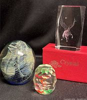 Group shot of all three paperweights: crystal Pegasus block, art glass egg, faceted glass with internal color