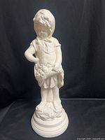 Full view of white clay child statue on pedestal base