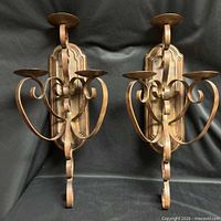 Front view of both metal wall sconces showing scroll design and three candle plates each