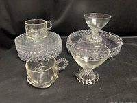 Full lot showing stack of beaded plates, two mugs with beaded handles, two footed dessert cups