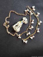 Necklace and figurine laid flat showing overall design