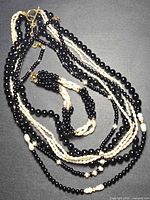 Full view of necklace and bracelet showing multiple strands of black obsidian beads and white pearls
