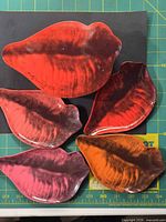 Five lip-shaped plates displayed on cutting mat showing colour variations and print detail
