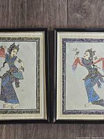 Both framed Balinese silk paintings side by side