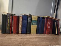 Full row of approximately 18 stamp albums standing on floor