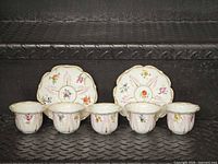 Front view of six cups and two dishes showing floral design and gilt rims
