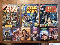 Group shot showing three oversize comics and six paperback novels