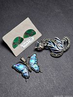 Front view of all three sterling silver jewelry items: earrings on card, butterfly pendant, cat brooch