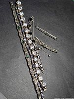 Overall view of four bracelets and bar pin on black background